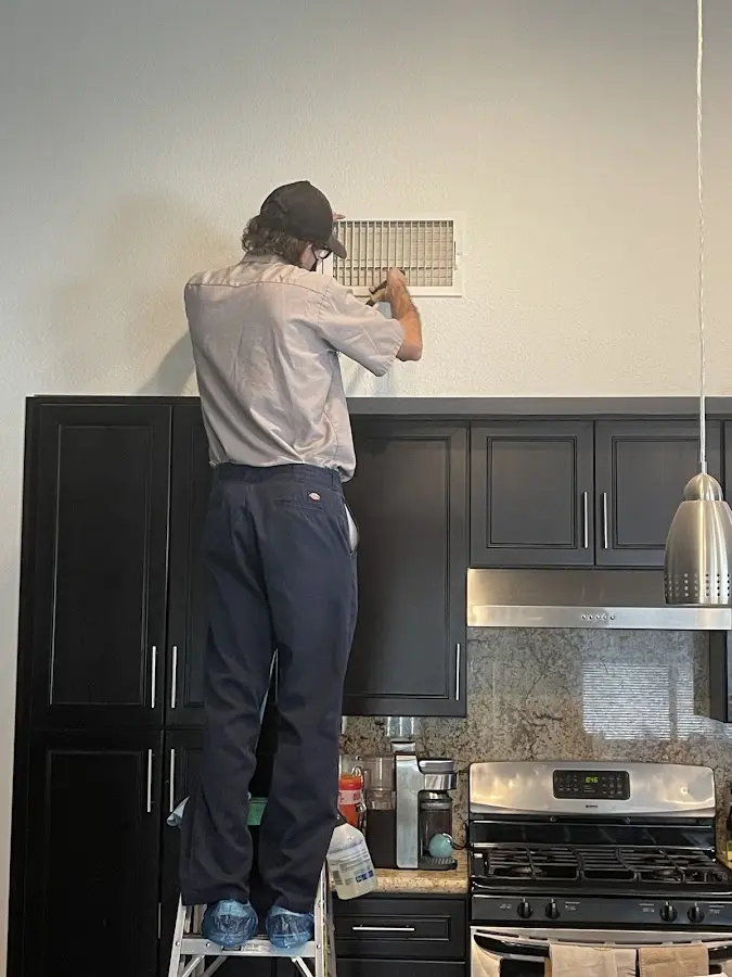 Technician inspecting an air vent during HVAC service in Titusville